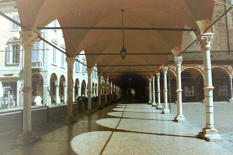 A covered station platform with repeating white columns and long afternoon shadows.